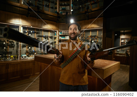 Crazy excited hunter weapon shop client laughing ominously standing with rifles 116090402