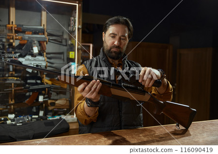 Salesman demonstrating professional accuracy gun assembly at counter desk 116090419