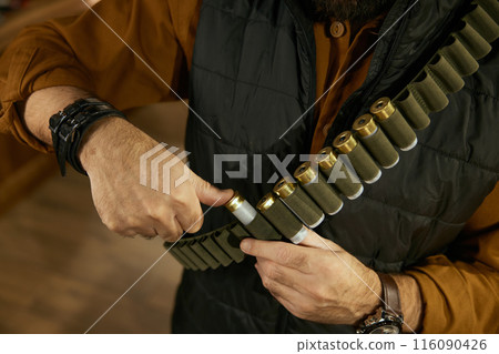 Hunter hands placing bullets into the ammo belt closeup 116090426