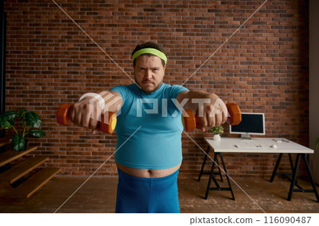 Portrait of serious comic man with obese figure doing workout with dumbbells 116090487