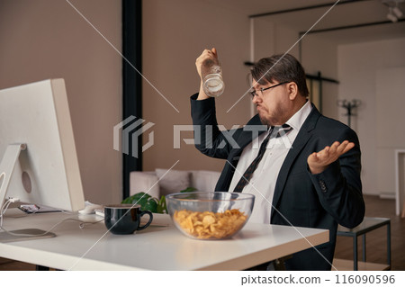 Businessman alcoholic fooling around with empty bottle at home office Businessman alcoholic fooling around with empty bottle at home office 116090596
