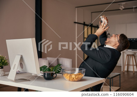 Businessman feeling tipsy drinking alcohol at home office workplace 116090604