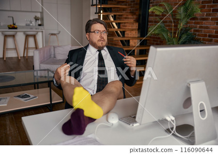 Funny businessman wearing formal suit put his legs on the desk working online Funny businessman wearing formal suit put his legs on the desk working online 116090644