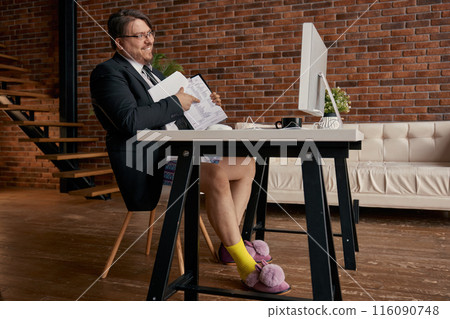 Funny geek businessman wearing formal suit and soft home slippers working online 116090748