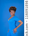 A woman in a blue dress is smiling and posing for the camera 116091898
