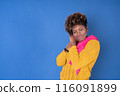 A woman in a yellow sweater is looking at the camera 116091899
