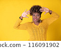Young pretty smiling black woman showing palms with curly afro hair, wearing yellow sweater on yellow background, with copy space. Happiness concept. 116091902