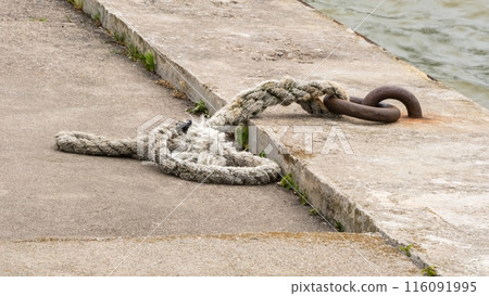 Frayed Rope Tied to Rusty Metal Hook on Pier 116091995