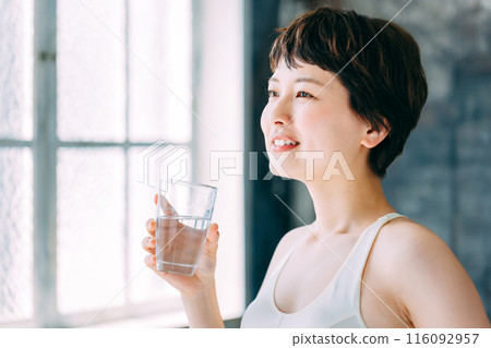 A woman holding a glass of water 116092957