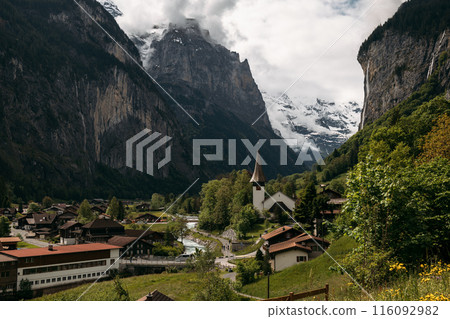 Discover a serene Swiss village embraced by mountains, offering an ideal setting for a peaceful alpine escape 116092982