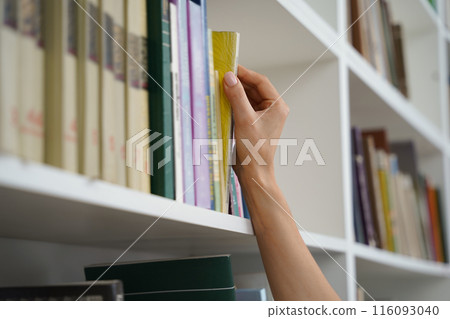Woman student studying taking book from shelf in library Woman student studying taking book from shelf in library 116093040