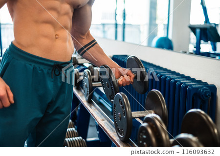 Bodybuilder holding a dumbbell in the gym 116093632