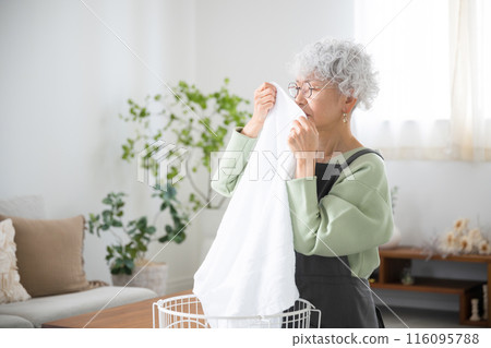 Close-up of a senior (elderly) woman who is troubled by smelly towels after drying laundry indoors during the rainy season Close-up of a senior (elderly) woman who is troubled by smelly towels after drying laundry indoors during the rainy season 116095788