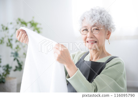 Close-up camera view of a senior woman who is troubled by smelly towels after drying laundry indoors during the rainy season 116095790