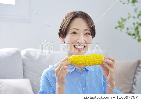Woman eating corn at home looking at camera 116097767