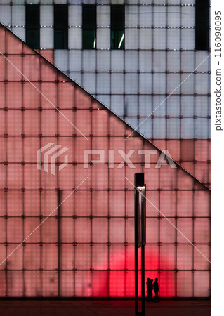 A family walking past the illuminated walls of Chongqing grand theatre in the night, an abstract yet cyberpunk scene. A family walking past the illuminated walls of Chongqing grand theatre in the night, an abstract yet cyberpunk scene. 116098095