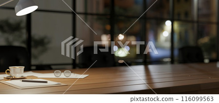 A dark meeting room at night, A wooden meeting table features a dim light from a lamp and decor. 116099563