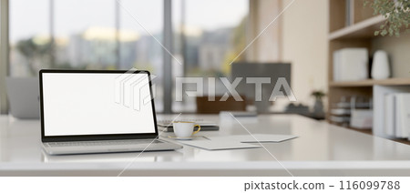 A laptop computer with a white-screen mockup on a meeting table in a modern meeting room. A laptop computer with a white-screen mockup on a meeting table in a modern meeting room. 116099788