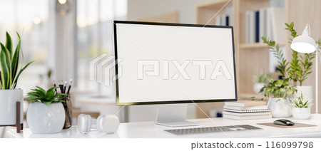 A computer desk featuring a computer mockup, books, headphones, and decorative plants. 116099798
