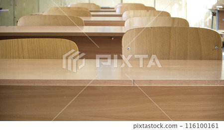 Empty classroom with wooden desks and chairs in sunlight Empty classroom with wooden desks and chairs in sunlight 116100161