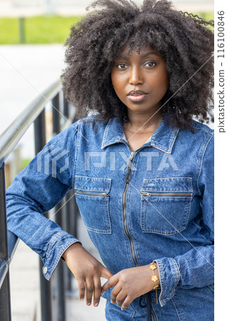 A stylish woman in a denim jacket exudes confidence and chic fashion effortlessly 116100846