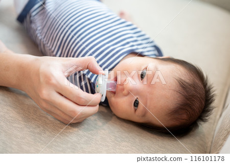 An adorable newborn baby lying on a couch with his pacifier. childhood concept 116101178