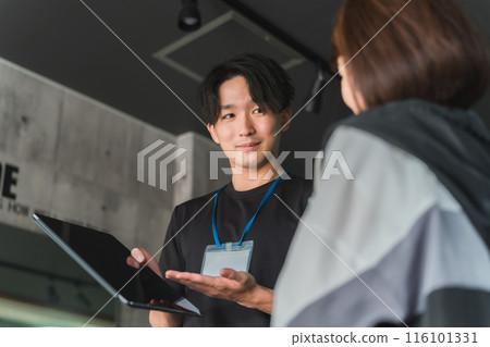 一位年輕的亞洲男性教練/教練向女性會員解釋和指導健身房的運動菜單。 一位年輕的亞洲男性教練/教練向女性會員解釋和指導健身房的運動菜單。 116101331