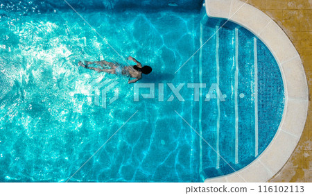 Woman swimming in pool on sunny day Woman swimming in pool on sunny day 116102113