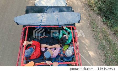 Adventure Journey in Utility Vehicle. Top view of a utility vehicle loaded with passengers and cargo, traveling on a dirt road, an outdoor excursion or adventure. 116102693