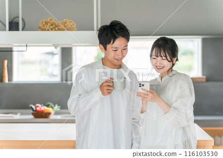 一對夫婦在家裡餐廳喝咖啡時看著智慧型手機 一對夫婦在家裡餐廳喝咖啡時看著智慧型手機 116103530