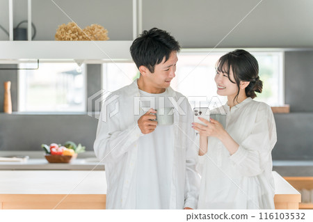 一對夫婦在家裡餐廳喝咖啡時看著智慧型手機 116103532