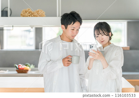 一對夫婦在家裡餐廳喝咖啡時看著智慧型手機 116103533