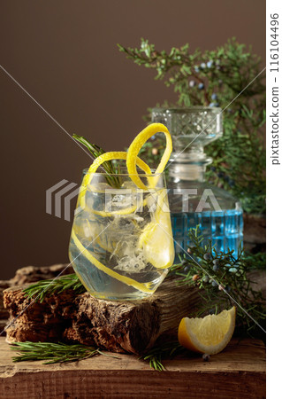 Cocktail gin-tonic with ice, lemon, and rosemary in a frozen glass. 116104496