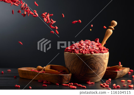 Dried goji berries in wooden bowl on a black background. 116104515