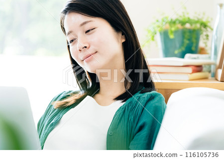 Young woman using a computer in the living room 116105736