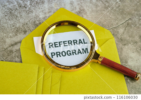Business concept. Text REFERRAL PROGRAM through a magnifying glass on a piece of mustard-colored envelope Business concept. Text REFERRAL PROGRAM through a magnifying glass on a piece of mustard-colored envelope 116106030