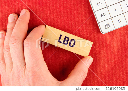 Business concept. Words Leveraged Buyout LBO written on wooden blocks with a hand, part of a calculator on a red background 116106085