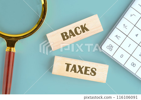 Business concept, copy space. Concept words BACK TAXES on wooden blocks in a composition with a magnifying glass and a calculator Business concept, copy space. Concept words BACK TAXES on wooden blocks in a composition with a magnifying glass and a calculator 116106091