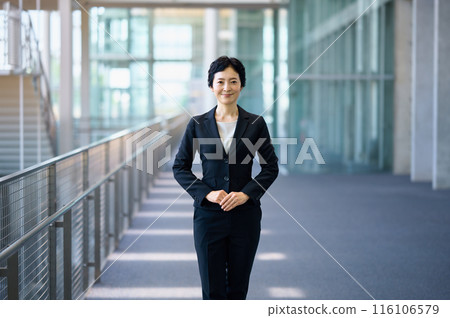 A middle-aged business woman in a suit standing in a hallway A middle-aged business woman in a suit standing in a hallway 116106579