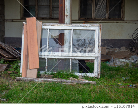 An old broken window among the debris. Construction rubbish. Dump. Place of repair An old broken window among the debris. Construction rubbish. Dump. Place of repair 116107014