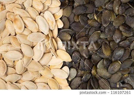 Unpeeled and peeled pumpkin seeds close-up, top view. 116107261