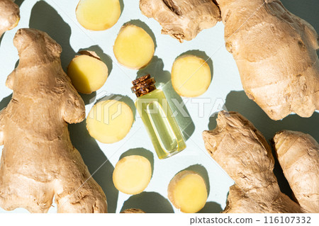Natural ginger oil in glass bottle among ginger roots. top view 116107332