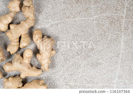 Fresh ginger roots on gray stone background close-up, space for text 116107368