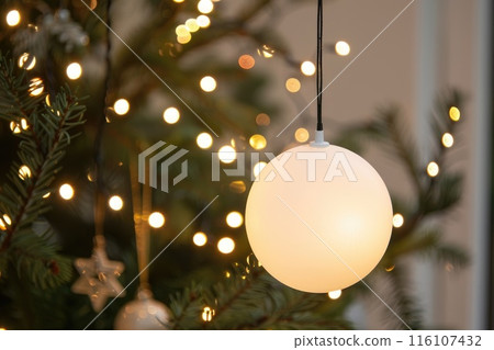 Sparkling Festive Morning with White Christmas Ornament and Twinkling Tree Lights Sparkling Festive Morning with White Christmas Ornament and Twinkling Tree Lights 116107432