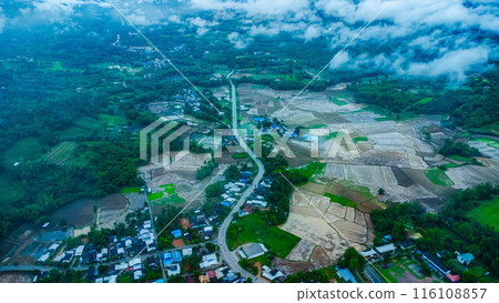 Aerial view of a beautiful rural village landscape in the middle of a nature valley during the rainy season and a stunning view of a flowing river in Loei Province, Thailand. 116108857