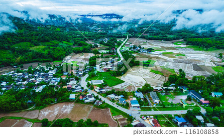 Aerial view of a beautiful rural village landscape in the middle of a nature valley during the rainy season and a stunning view of a flowing river in Loei Province, Thailand. Aerial view of a beautiful rural village landscape in the middle of a nature valley during the rainy season and a stunning view of a flowing river in Loei Province, Thailand. 116108858
