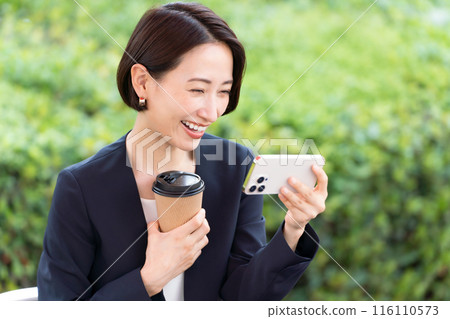 Woman looking at smartphone on terrace 116110573