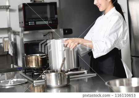 Young Asian female chef cooking in a stockpot Young Asian female chef cooking in a stockpot 116110653