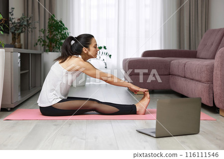 fit Caucasian woman worm up by stretching her body on pink exercise mat at home 116111546