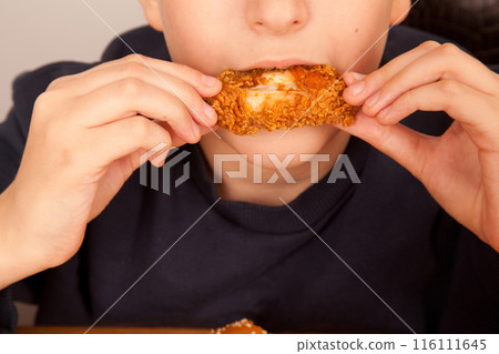 Caucasian man eating fried chicken wings, American fast food culture, cooked chicken pieces Caucasian man eating fried chicken wings, American fast food culture, cooked chicken pieces 116111645